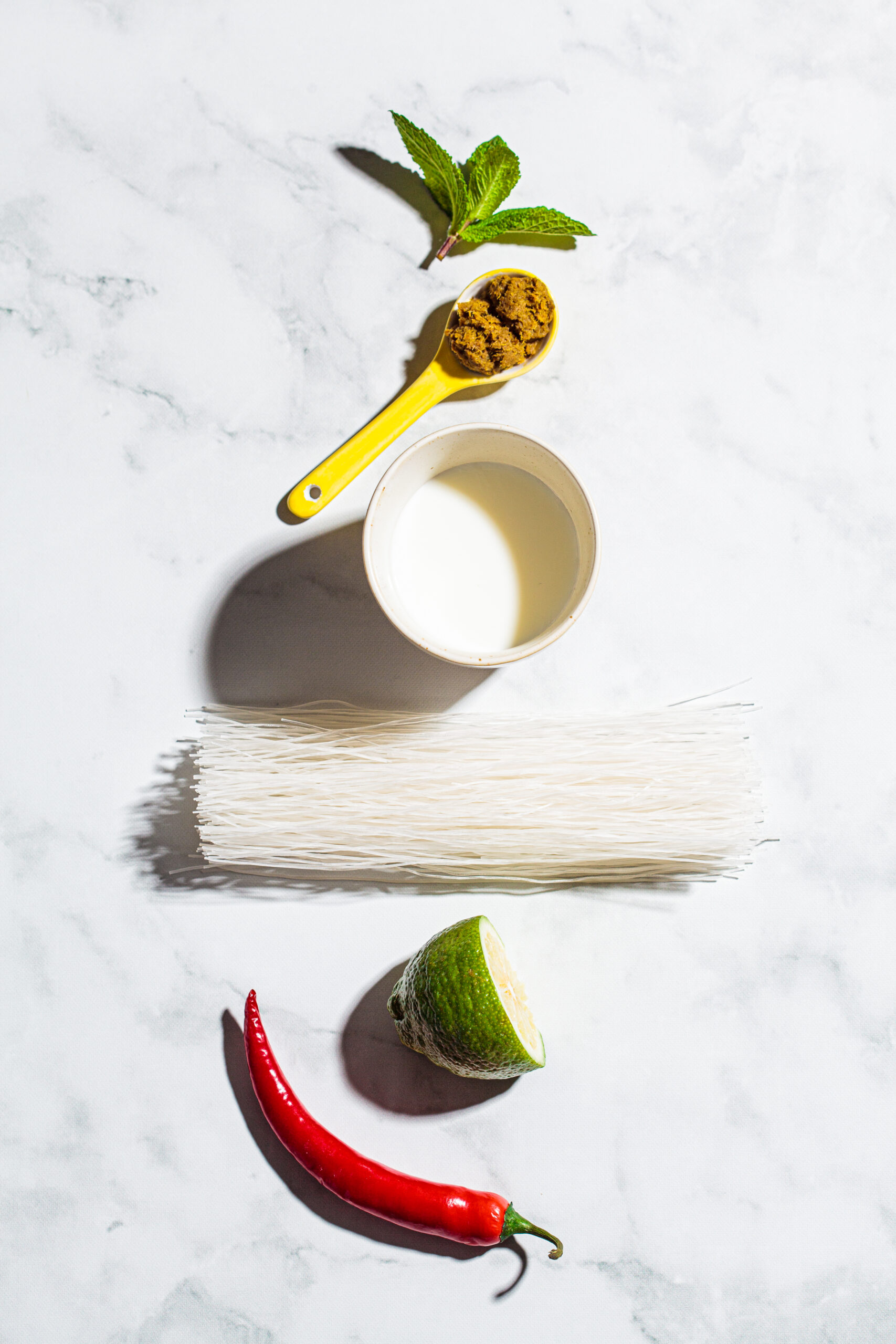 Flat lay of ingredients for thai green curry on white marble background, copy space.